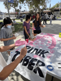 Team Members Painting a Pinktober Poster